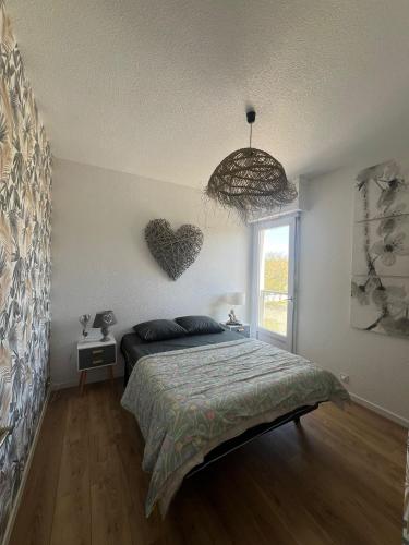 a bedroom with a bed and a heart on the wall at Appartement face golf et océan in Saint-Jean-de-Monts