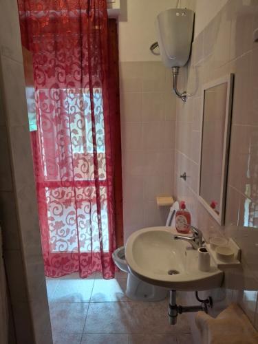 a bathroom with a sink and a red shower curtain at NEN's House in Alghero