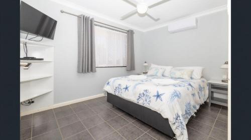 a bedroom with a bed with a blue and white comforter at Ocean Beach Chalet 18 in Jurien Bay