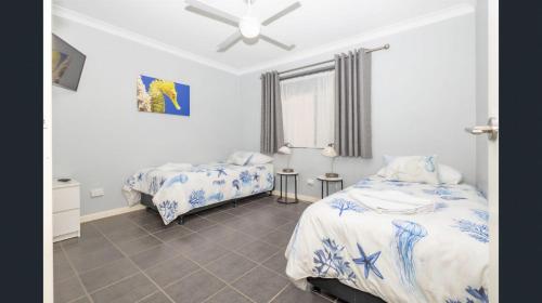 a bedroom with two beds and a ceiling fan at Ocean Beach Chalet 18 in Jurien Bay