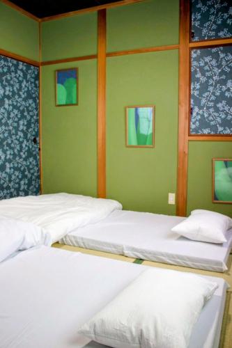 three beds in a room with green walls and windows at ゲストハウス青い輝き in Marugame