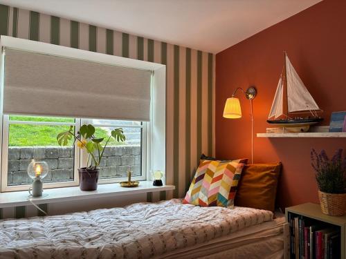 a bedroom with a bed and a window with a sailboat at Charming holiday home on the harbour (5 persons) in Rødvig