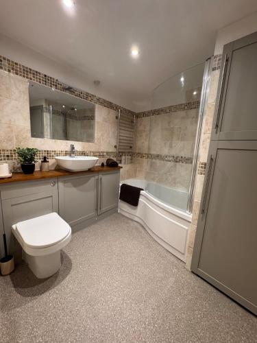 a bathroom with a tub and a toilet and a sink at Hollins Mill Apartment in Sowerby Bridge