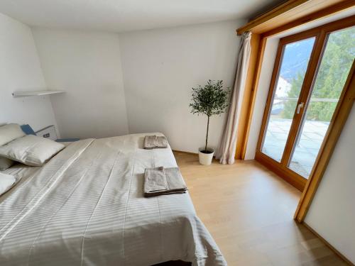 a bedroom with a large bed and a potted plant at Alpine Home with Lounge - 10 min from St Moritz in La Punt-Chamues-ch