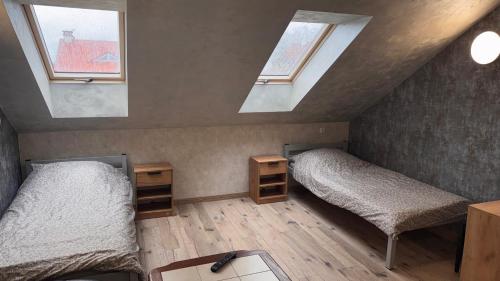 a attic room with two beds and two windows at Apartament 4 Słoneczna in Ełk