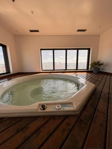 a large jacuzzi tub in a room with windows at MN Gotado Hotel Flat Guarulhos Aeroporto in Guarulhos