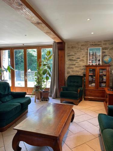 a living room with a wooden table and green chairs at Chez Baptistète in Labastide