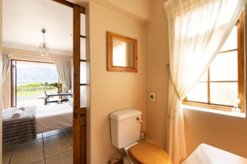 a bathroom with a toilet and a bed and a window at Coastline Serenity in Kleinmond