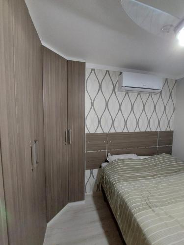 a bedroom with a bed and wooden cabinets at Apartamento prox Praça Nova Shopping in Araçatuba