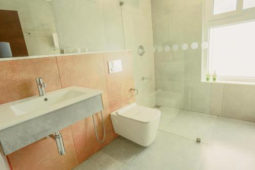 a white bathroom with a sink and a toilet at Crayons Guest House Munnar in Munnar