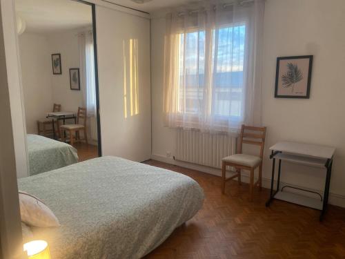 a bedroom with two beds and a table and a window at Maison Mylan, simple and practical! in Cholet