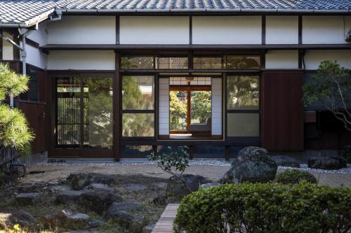 a house with windows and rocks in front of it at 3000平米の元醤油名家邸宅, 日本庭園, 蔵Bar, サウナ, 出張料理, フルサービスの宿 in Shodoshima
