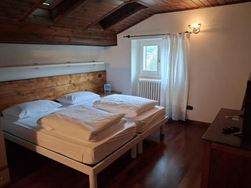 two twin beds in a room with a window at B&b Villa Giò in Cremeno