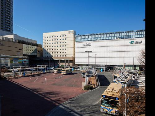 a parking lot with buses parked in front of a building at JR-East Hotel Mets Yokohama Tsurumi in Yokohama