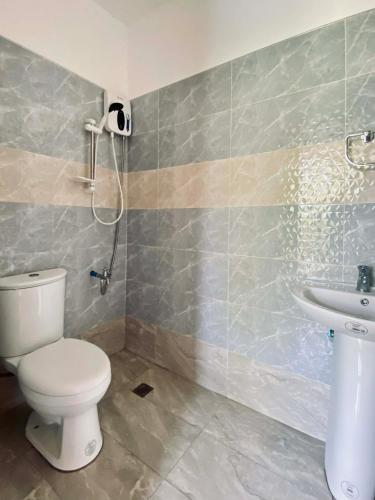 a bathroom with a toilet and a sink at The Grey House in Bacong