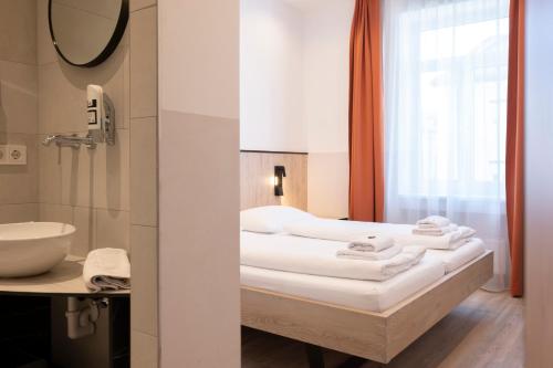 a bathroom with a bed and a sink and a mirror at Villa Flöckner Bed & Breakfast in Salzburg