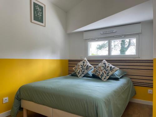 a bedroom with a bed with yellow walls and a window at Au petit lavoir in Trévières
