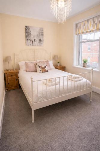 a bedroom with a large white bed with a chandelier at Clock Tower Flats Morpeth in Morpeth