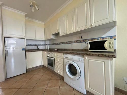 a kitchen with white cabinets and a washer and dryer at Apartmán Centrum in Los Cristianos