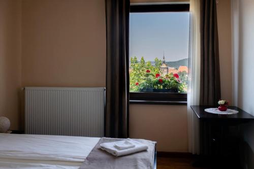 a bedroom with a bed and a window with flowers at Panorama Guesthouse in Sighişoara