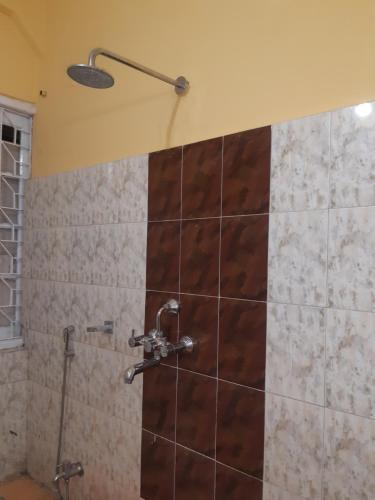 a shower with a shower head on a tiled wall at Himalayan Heritage Stay in Darjeeling
