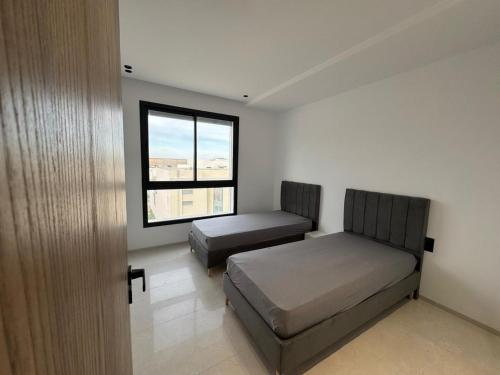 a bedroom with two beds and a window at Résidence Jasmin in Harqalah