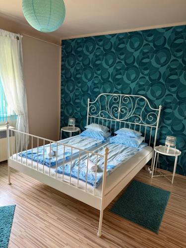 a bedroom with a bed with a green wall at Zso-Zé Apartman in Tiszafüred