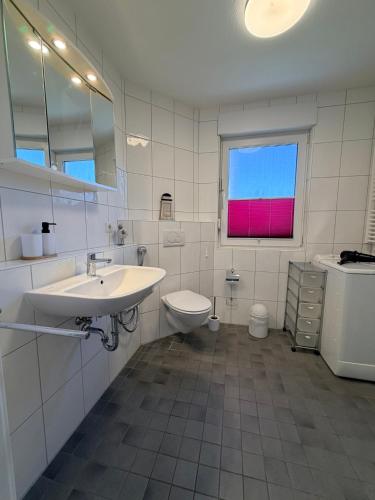 a bathroom with a sink and a toilet and a window at Duhner Leuchturm, Ferienwohnung DL02 in Cuxhaven
