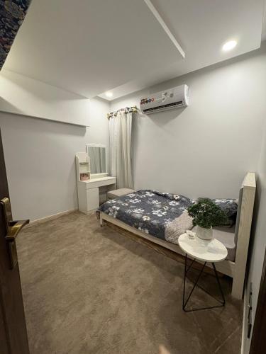 a small bedroom with a bed and a table at Talya Apartment in Mecca