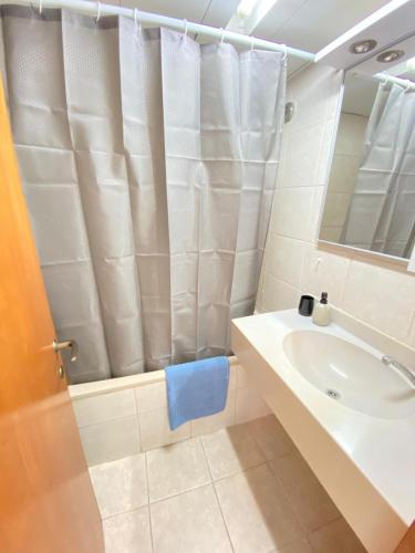 a bathroom with a shower curtain and a sink at Pure Bliss Caesarea - אושר טהור בקיסריה in Caesarea