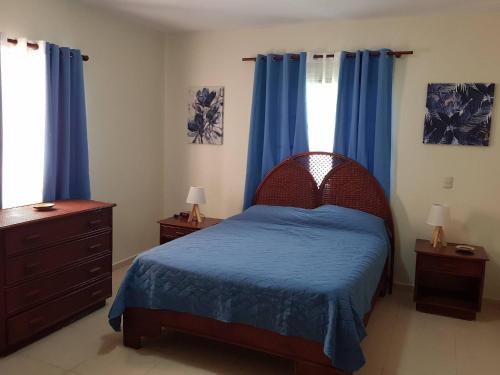 a bedroom with a bed with blue sheets and blue curtains at 2BR Condo with Pool, Walk to Beach, Bvaro in Punta Cana