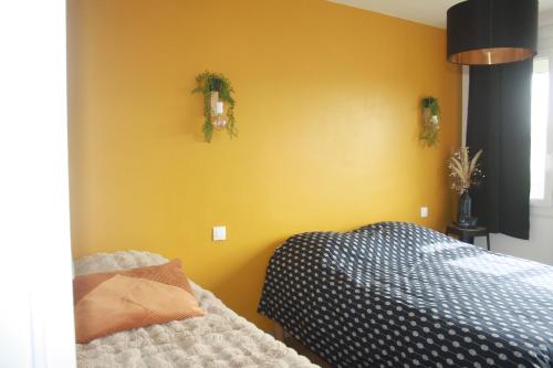 a bedroom with a bed and a yellow wall at Le cosy de Cholet près du PUY DUFOU in Cholet