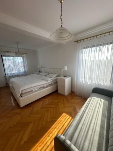 a bedroom with a large white bed and wooden floors at Grand apartman in Banja Luka