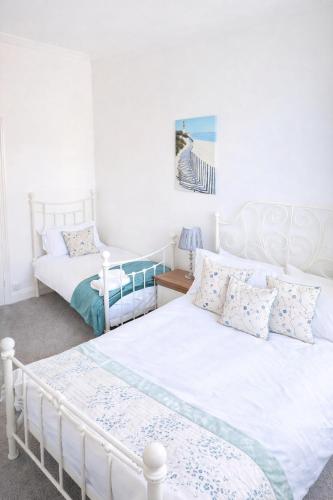two beds in a bedroom with white walls at Sea Thrift Nook Amble in Amble