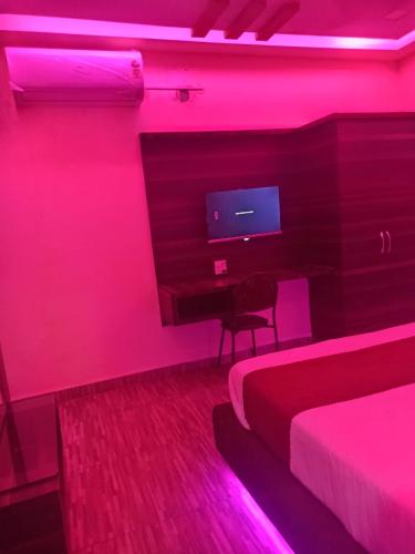 a bedroom with a red lighted room with two beds and a television at hotel shree shyam palace in Ujjain