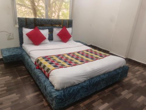 a bed with red pillows on it in a room at hotel shree shyam palace in Ujjain
