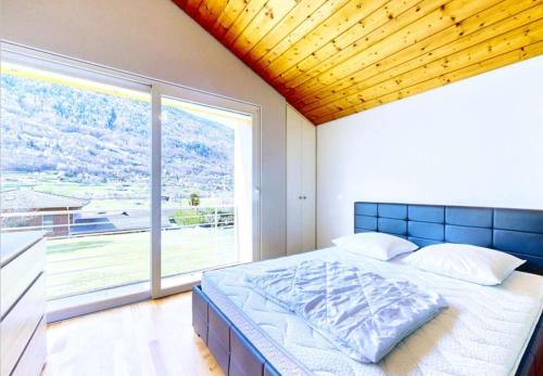 a bedroom with a bed and a large window at BluVilla in Malvaglia