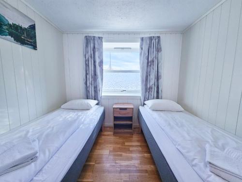 two beds in a small room with a window at Apartment close to the mountain in Svolvær