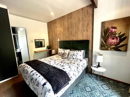 a bedroom with a bed and a painting on the wall at Naby-My Stellenbosch Cottage in Stellenbosch