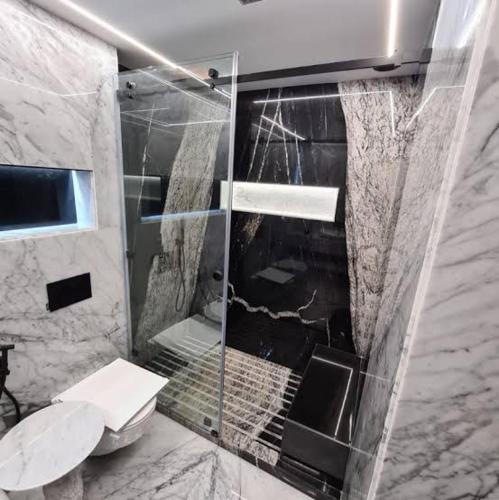 a bathroom with a glass shower with a toilet at Apartment Modern zeganrif in Segangane