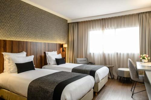 a hotel room with two beds and a table and a desk at Apartment Modern zeganrif in Segangane