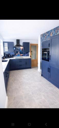 a large kitchen with blue cabinets and a tile floor at Cambois beach Maisonette with sea view! in Cambois