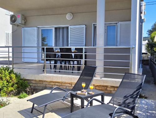 a patio with two chairs and a table with wine glasses at Beach House Adria in Bibinje