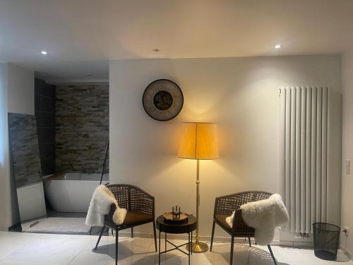 a living room with two chairs and a table and a clock at Moderne, ruhige Ferienwohnung , ideal zum Abschalten in Hadamar