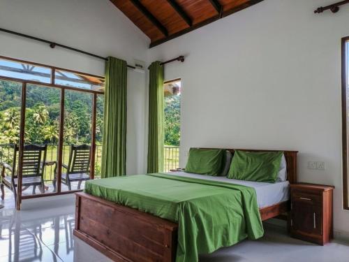 a bedroom with a bed with green sheets and a balcony at Forest & Fields Sinharaja in Deniyaya