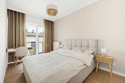 a white bedroom with a large bed and a desk at Neon Apartments Centrum in Częstochowa