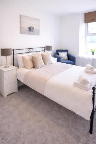 a bedroom with a large white bed and a blue chair at Coquet Nest AMBLE in Amble