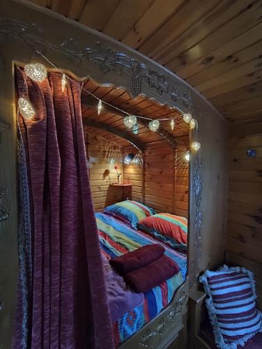 a bed in a log cabin with a canopy at Les roulottes Vesta in Léognan