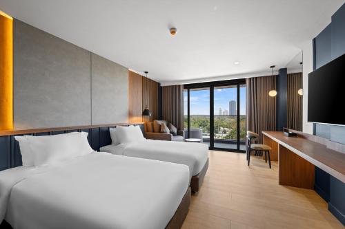 a hotel room with two beds and a television at The Turtle Hotel Bangsaen in Ban Thai Don (1)