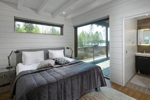 a bedroom with a bed and a large window at Arkkitehtihuvila järvinäköalalla 5 makuuhuonetta ja tilauspalveluna ulkoporeallas in Ähtäri